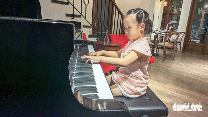 4 tháng học đàn, giành giải vàng cuộc thi piano toàn quốc- Ảnh 1. Bé Thái Tuệ Nghi (5 tuổi) biểu diễn piano ngẫu hứng tại một quán cà phê ở TP Huế - Ảnh: NHẬT LINH